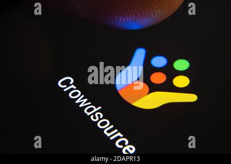 Stafford / Vereinigtes Königreich - November 12 2020: Google Crowdsource App und verschwommene Fingerspitze darüber bereit, den Bildschirm des Smartphones zu drücken. Stockfoto