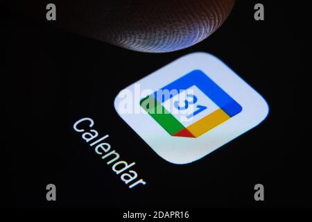 Stafford / Vereinigtes Königreich - November 12 2020: Google Kalender App und verschwommene Fingerspitze darüber bereit, den Bildschirm des Smartphones zu drücken. Stockfoto