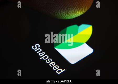 Stafford / Großbritannien - November 12 2020: Snapseed App und verschwommene Fingerspitze darüber bereit, den Bildschirm des Smartphones zu drücken. Stockfoto