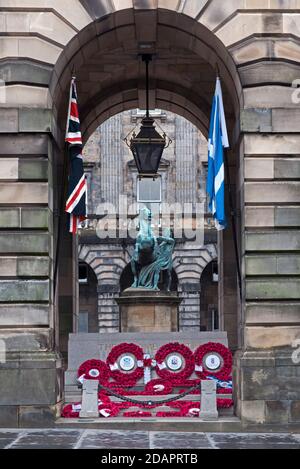 Mohnkränze und der Stein der Erinnerung vor den City Chambers in Edinburgh zusammen mit der Union Jack und der Scottish Saltyre Flagge. Stockfoto