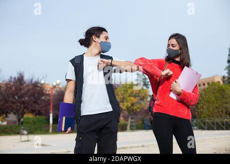 Zwei Universitätsstudenten stoßen ihre Ellbogen an, anstatt sich zu umarmen. Vermeiden Sie die Ausbreitung von Coronavirus, soziale Distanz. Stockfoto