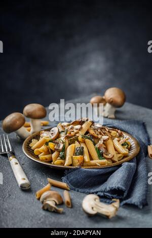 Pasta Penne mit gerösteten Pilzen, Knoblauch und Zucchini. Italienische Küche auf blauem Marmortisch. Stockfoto