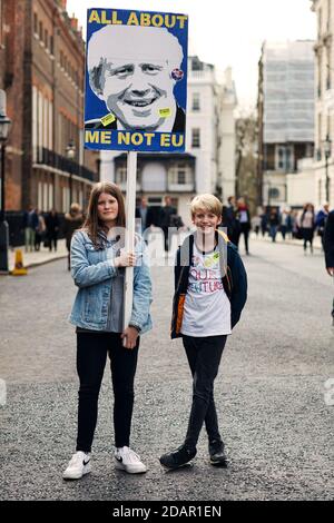 LONDON, Großbritannien - zwei junge Anti-brexit-Demonstranten halten während der Anti-Brexit-Proteste am 23. März 2019 in London ein Plakat gegen Boris Johnson. Stockfoto