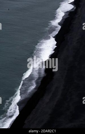 Blick von oben auf Wellen am Ufer, schwarzer Lavastrand am Nordatlantik, Motion Blur, Cape Dyrholaey, Vik i Myrdal, Südisland Stockfoto