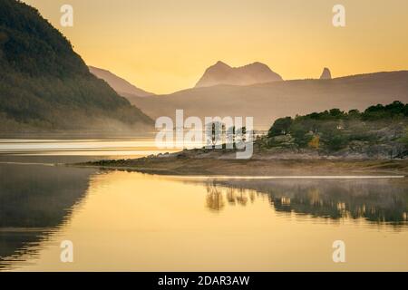 Fjord im Abendlicht im Dunst, vor Insel mit borealen Wald, im hinteren Gebirge, Innhavet, Nordland, Norwegen Stockfoto