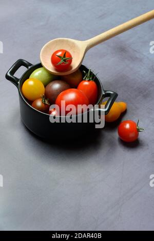 Verschiedene Kirschtomaten im Topf mit Kochlöffel, Deutschland Stockfoto