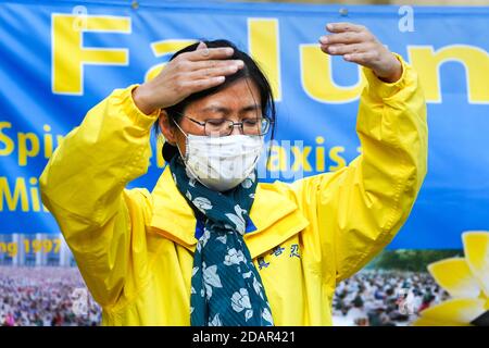 Dortmund, Deutschland, 14. 2020. November: Eine Frau praktiziert Falun Gong Meditation mit Gesichtsmaske während eines Protestes gegen die Verfolgung von Falun Gong Anhängern in China Stockfoto