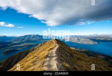 Wanderer auf einem Bergrücken, Blick auf Berge und See vom Mount Roy, Roys Peak, Lake Wanaka, Southern Alps, Otago, South Island, Neuseeland Stockfoto