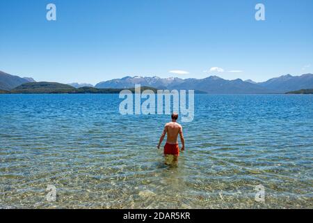 Der junge Mann badet im See, Lake Manapouri, Fraser Beach, Manapouri, South Island, Neuseeland Stockfoto