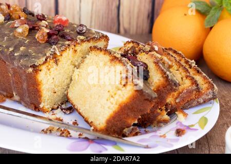 Hausgemachter Zitronen- und Orangenpudding mit in Scheiben geschnittenen Früchten auf einer weißen Platte mit Blumenzeichnungen im Vintage-Stil auf einem Holztisch, etwas Zitrusfrüchte fru Stockfoto