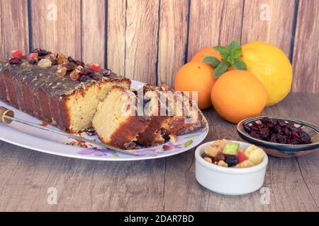 Hausgemachter Zitronen- und Orangenpudding mit in Scheiben geschnittenen Früchten auf einer weißen Platte mit Blumenzeichnungen im Vintage-Stil auf einem Holztisch, etwas Zitrusfrüchte fru Stockfoto