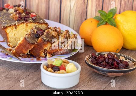 Hausgemachter Zitronen- und Orangenpudding mit in Scheiben geschnittenen Früchten auf einer weißen Platte mit Blumenzeichnungen im Vintage-Stil auf einem Holztisch, etwas Zitrusfrüchte fru Stockfoto