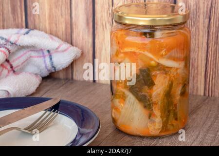 Kimchi-Kohl-Glas, typisch würzige koreanische Küche in einem rustikalen Rahmen bereit, auf einem Teller zu dienen. Stockfoto