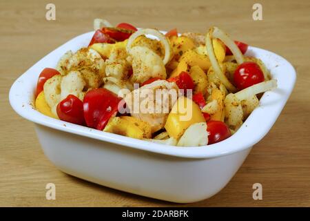 Geschmortes Huhn mit Gemüse in einer weißen Schüssel. Gebackene Hähnchenstücke mit Paprika und Blumenkohl Stockfoto