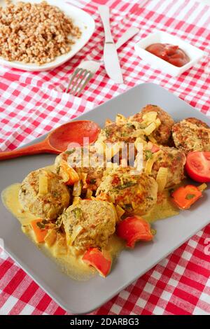 Fleischbällchen mit Gemüse auf einem blauen Teller.Buchweizenbrei und Ketchup.rot Karierte Tischdecke Stockfoto