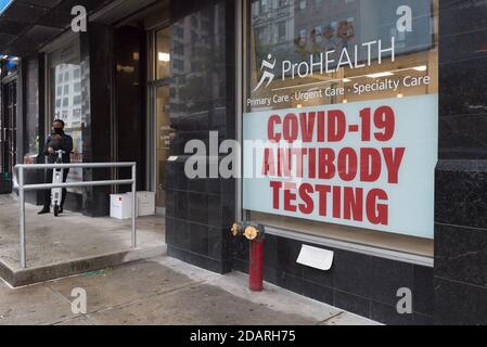 Manhattan, New York. 13. November 2020. Eine Frau außerhalb einer Klinik auf der 3. Straße mit einem Schild, das COVD-19-Antikörpertests anbietet. Stockfoto