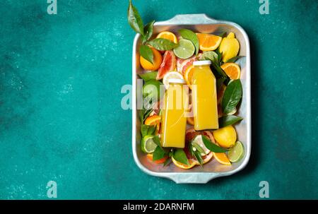 Zwei Flaschen Zitrussaft und Scheiben frischer Zitrusfrüchte auf türkisfarbenem Hintergrund, Draufsicht Stockfoto