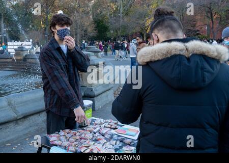 New York, Usa. November 2020. Ein Mann trägt eine Gesichtsmaske und übergibt Cookies und sammelt Spenden, um im Washington Square Park inmitten einer Coronavirus-Pandemie (Covid-19) in New York City gegen Kinderkrebs zu kämpfen. Kredit: SOPA Images Limited/Alamy Live Nachrichten Stockfoto