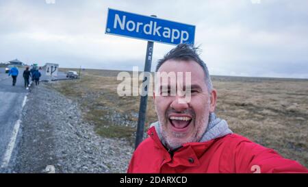 Nordkapp, Norwegen - Juni 2016: Tourist macht ein glückliches Selfie unter dem Nordkapp-Schild, dem nördlichsten Punkt Europas Stockfoto