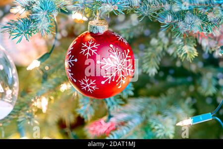 Rot glitzernde Kugel auf verschwommenem weihnachtsbaum Hintergrund mit Urlaub Leuchtet Stockfoto