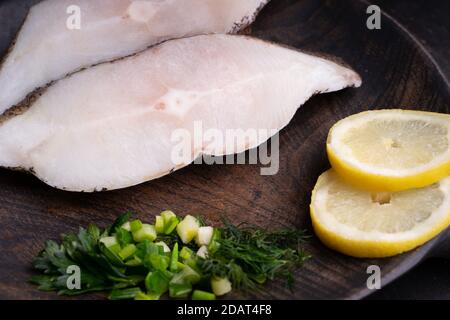 Gefrorene grönländische Heilbutt-Steaks auf dem Holzschneidebrett. Hintergrund für das Essen. Draufsicht Stockfoto