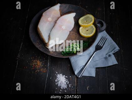 Gefrorene grönländische Heilbutt-Steaks auf dem Holzschneidebrett. Hintergrund für das Essen. Draufsicht Stockfoto