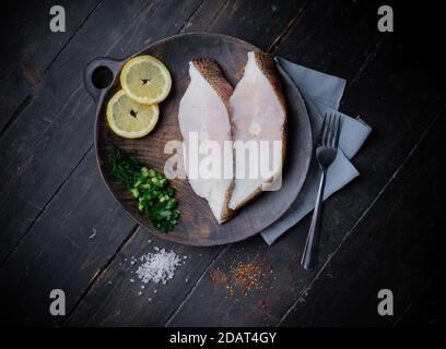 Gefrorene grönländische Heilbutt-Steaks auf dem Holzschneidebrett. Hintergrund für das Essen. Draufsicht Stockfoto
