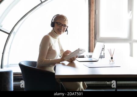 Lächelnde Geschäftsfrau mit Headset am Schreibtisch Stockfoto