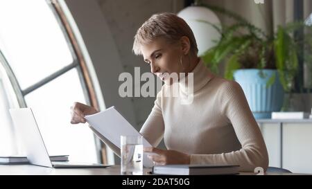 Selbstbewusste seriöse Geschäftsfrau, die mit Dokumenten im modernen Büro arbeitet Stockfoto
