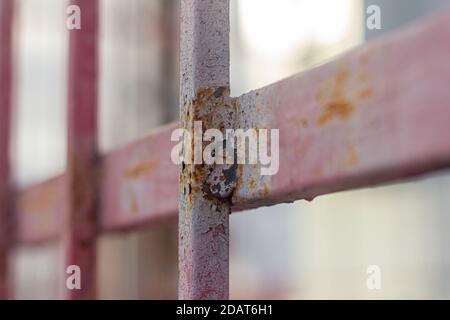 Fragment eines Metallzauns mit Rostflecken durch rosa Farbe Stockfoto