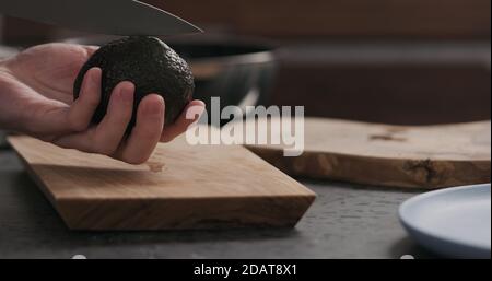 Zeitlupe Mann schneidet reifen Avocado auf Küche zu öffnen, breites Foto Stockfoto