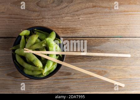 Japanische Vorspeise Edamame grüne Sojabohnen gewürzt mit Salz in einer Schüssel, mit Shop-Sticks auf der Seite. Stockfoto