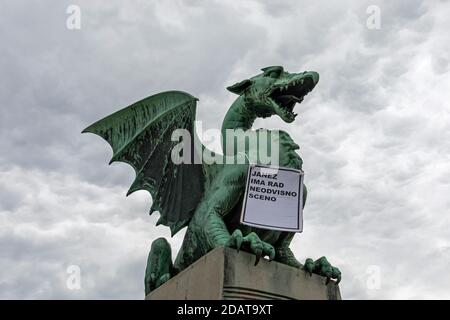 Drachenstatue an der Drachenbrücke in Ljubljana mit einem Schild gegen Sloweniens Ministerpräsidenten Janez Jansa, Slowenien Stockfoto