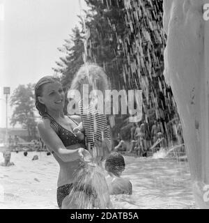 Mutter hält junge Tochter unter Brunnen im öffentlichen Schwimmbad Ungarn der 1970er Jahre Stockfoto