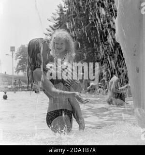 Mutter hält junge Tochter unter Brunnen im öffentlichen Schwimmbad Ungarn der 1970er Jahre Stockfoto