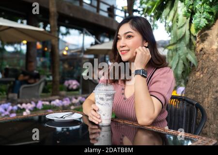 Junge Frau trinkt Eismilch Frappe in einem Café Stockfoto