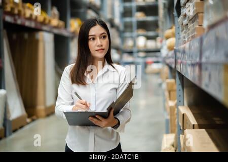 Junge Frau Arbeiter hält Zwischenablage und Überprüfung Inventar in der Lagerhaus Stockfoto