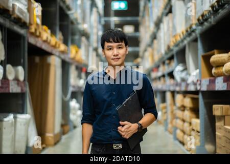 Junger Mann Arbeiter hält Zwischenablage und Überprüfung Inventar in der Lagerhaus Stockfoto