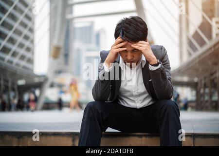 Gestresster Geschäftsmann sitzt auf dem Boden in der Stadt Stockfoto