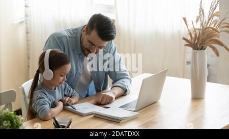 Fürsorglicher Vater hilft kleinen Tochter mit Schulaufgaben zu Hause Stockfoto