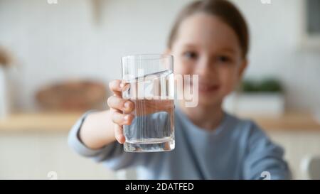 Close up kleines Mädchen hält Wasserglas, bietet Kamera Stockfoto