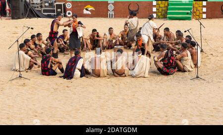 Naga Männer siting und die Frauen Folk Durchführung einer traditionellen Stammesritual in Nagaland Indien während des Hornbill-Festivals am 4 Dezember 2016 Stockfoto