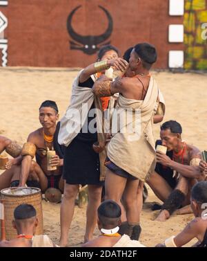 Naga Männer und Frauen, die einen traditionellen Stammes sitzend und durchführen Ritual im Kisama Dorf in Nagaland Indien während des Hornbill Festivals Am 4. Dezember 2016 Stockfoto