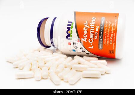 Jetzt Lebensmittel, Acetyl-L-Carnitin, 500 mg, 100 Veg Kapseln und mehrere vor der Flasche verstreut. Isoliert auf weißem Hintergrund. Stockfoto