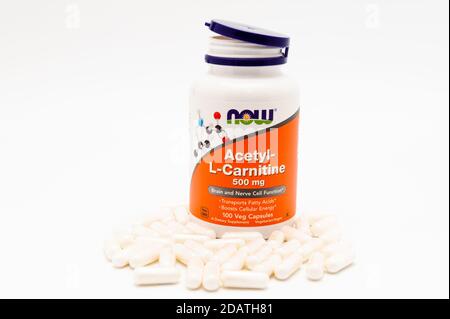 Jetzt Lebensmittel, Acetyl-L-Carnitin, 500 mg, 100 Veg Kapseln und mehrere vor der Flasche verstreut. Isoliert auf weißem Hintergrund. Horizontale Aufnahme. Stockfoto