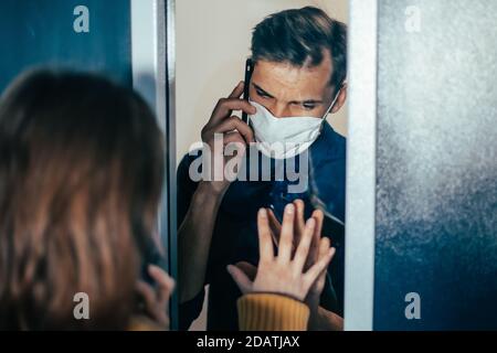 Junger Mann und eine Frau schauen sich ängstlich durch das Glas an. Stockfoto