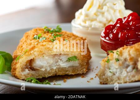 Abschnitt von gebratenem Fisch mit Ketchup und Mayonnaise im Hintergrund - Nahaufnahme Stockfoto