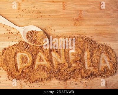 Das Wort 'PANELA' ist mit Krümel auf einer hölzernen Oberfläche geschrieben Stockfoto
