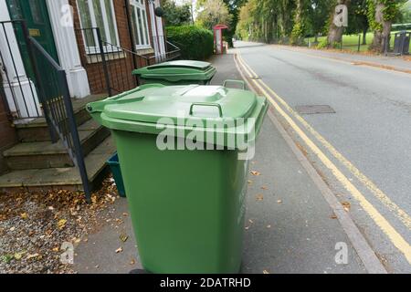 Grüne Gartenabfallbehälter an einer Bordwand warten darauf geleert zu werden. Grüne Behälter werden zum Sammeln und Recycling von Pflanzen und Gemüseanfällen verwendet Stockfoto