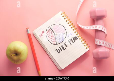 Diätplan mit Mandelnuss, Hanteln, Apfel auf dem Tisch Stockfoto